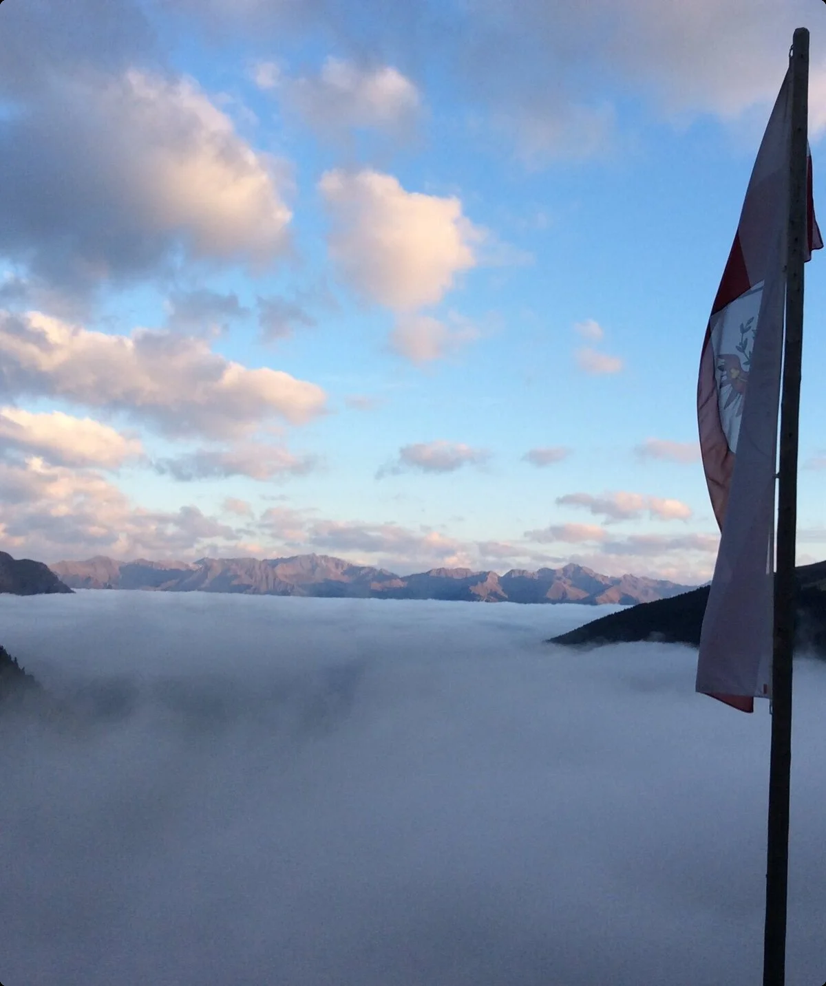 Nebeliger Blick vom Hohenzollernhaus ins Tal mit Fahne im Vorder- und Bergpanorama im Hintergrund über dem Nebel | © DAV Starnberg