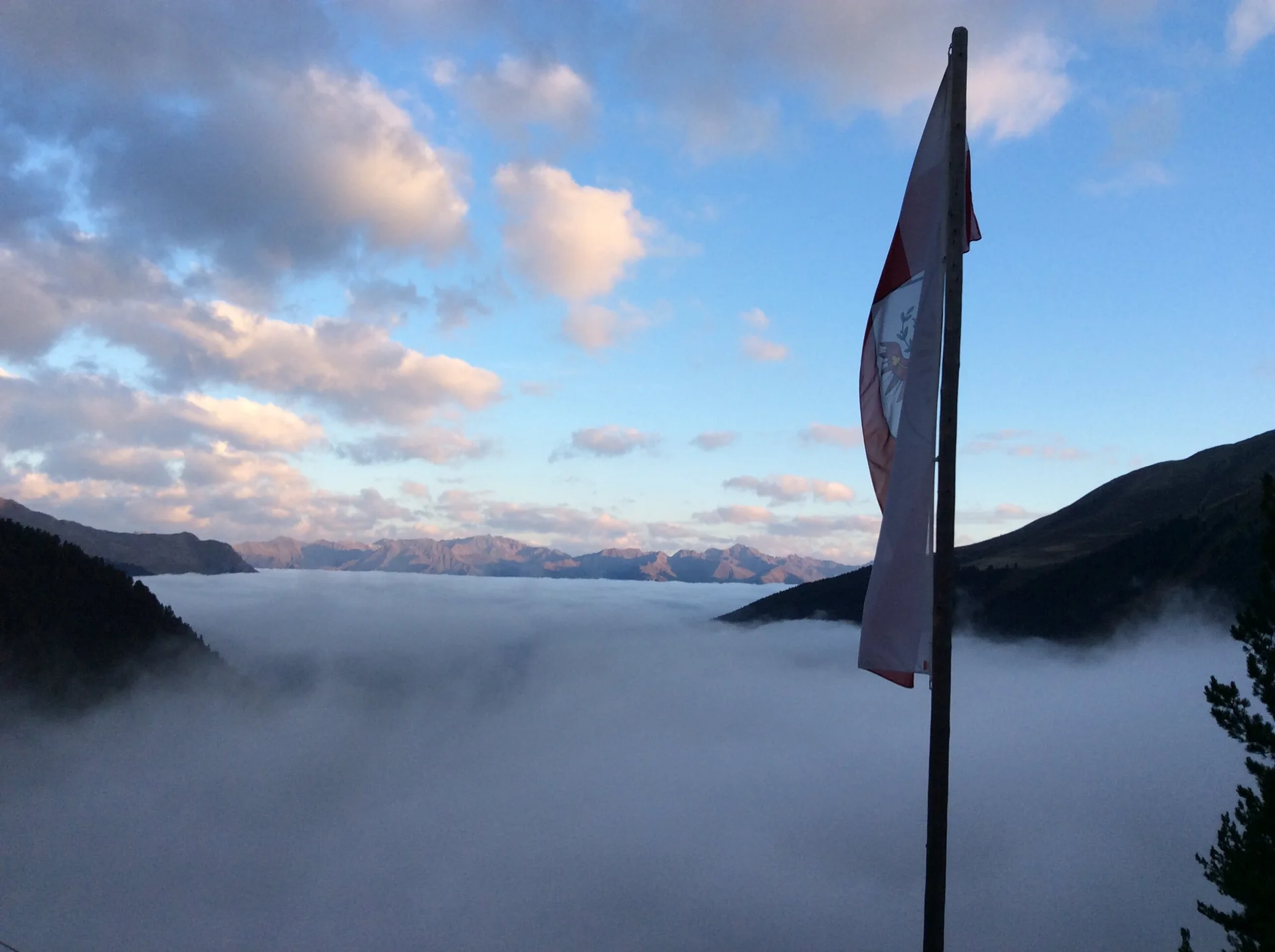 Nebeliger Blick vom Hohenzollernhaus ins Tal mit Fahne im Vorder- und Bergpanorama im Hintergrund über dem Nebel | © DAV Starnberg