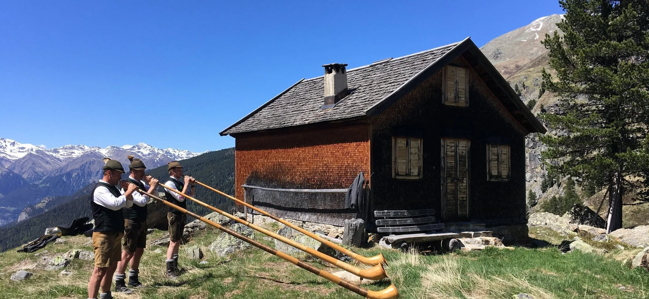Hohenzollernhaus Alphornbläser vor Nebenhütte und Berggipfeln | © DAV Starnberg