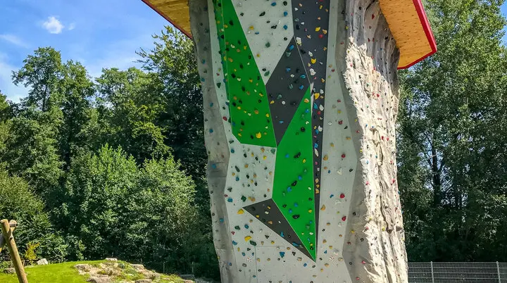 Foto Kletterturm mit Bank, Wiese, Reck, Stein mit Slackline, Wald im Hintergrund | © Walltopia: Bild aufgerufen am 28.11.2024 von: https://walltopia.com/de/projects/dav-starnberg-outdoor-tower/